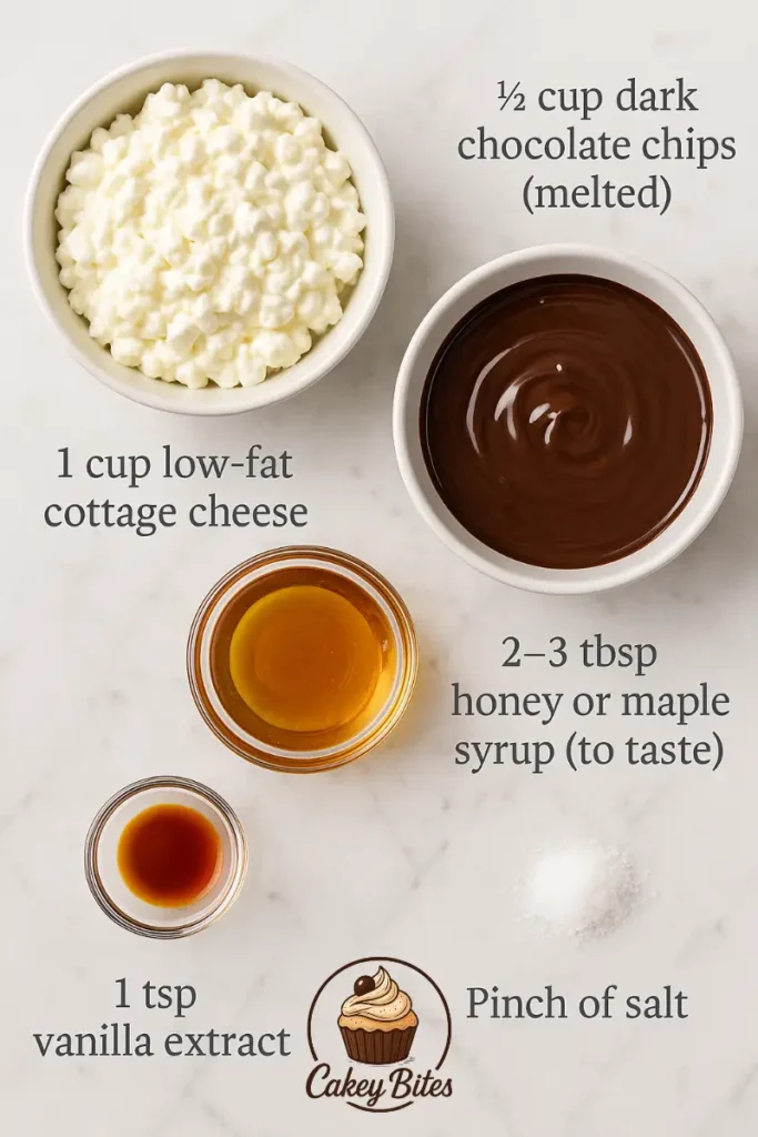 Ingredients for cottage cheese chocolate mousse: cottage cheese, melted chocolate, sweetener, vanilla, and salt. Top-down view of ingredients for cottage cheese chocolate mousse: low-fat cottage cheese, melted dark chocolate chips, honey or maple syrup, vanilla extract, and a pinch of salt.