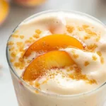 Creamy vanilla protein powder peach shake in an elegant glass, with peach slices and vanilla pods—perfect as the featured image for vanilla protein powder peach shake recipes.